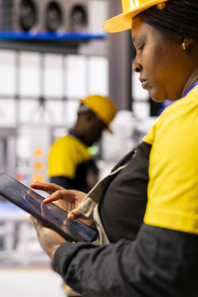 Closeup of engineer utilizing tablet to program and streamline industrial automation, ensuring production efficiency in industry 4.0 facility. Female technician developing automated machinery.